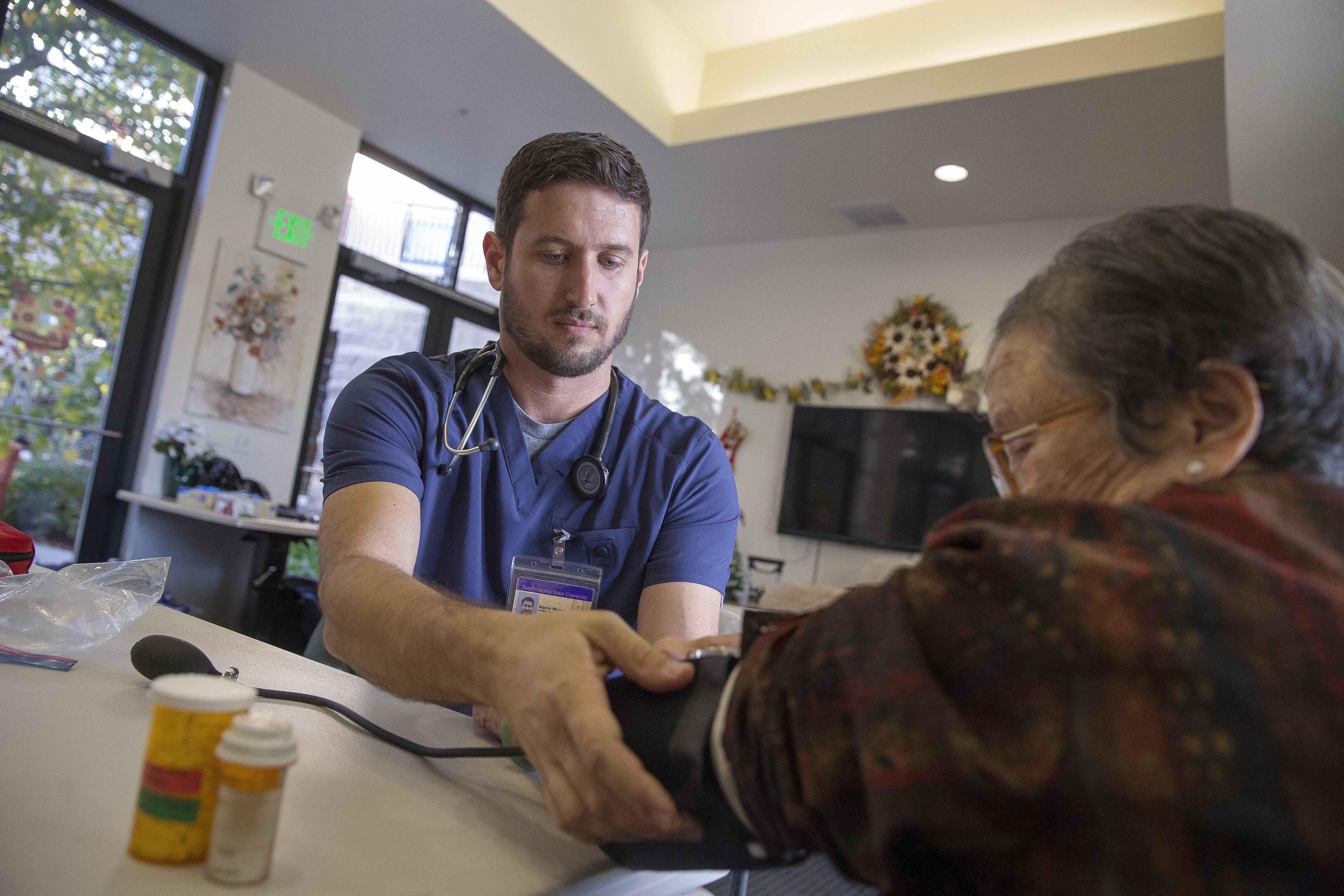 A student checking a blood pressure of an elderly patient